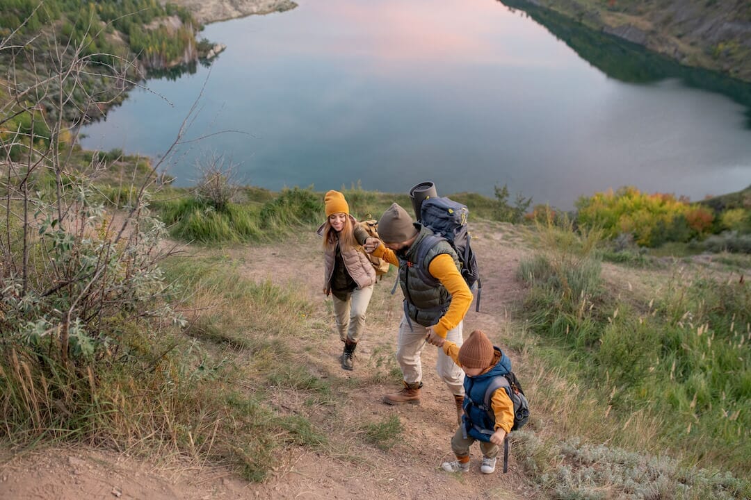 A girl, a boy and their father hiking.